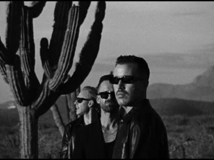 Three men posing in desert landscape