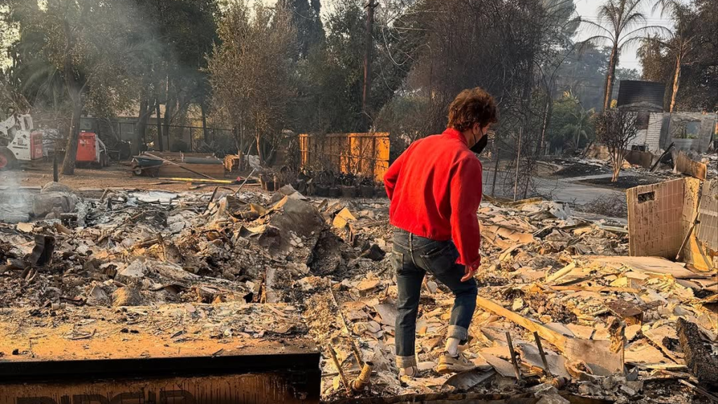 Woman examining fire-damaged house ruins