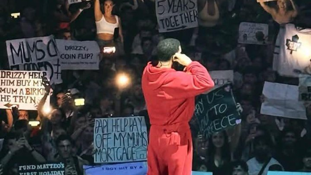 Drake performing, fans holding money signs